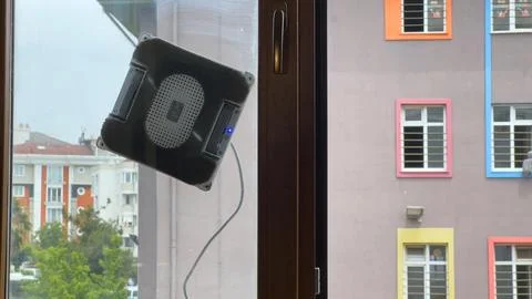 Dirty windows. Robot cleaner washes glass against the backdrop of multi store Stock Photos