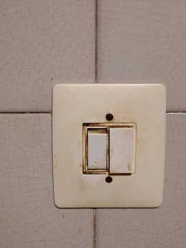 Dirty worn light switch on cracked tile wall Stock Photos