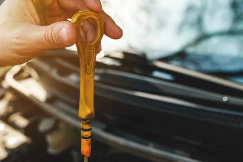 Dirty yellow handle from a car engine dipstick in hand Stock Photos