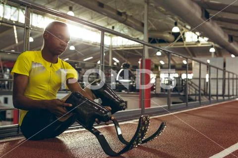 Disabled African American male athletic sitting on race track in fitness center Stock Photos
