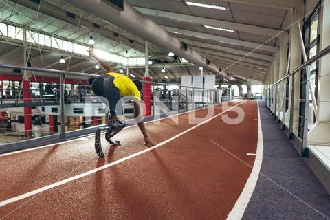 Disabled African American male athletic running on race track in fitness center Stock Photos