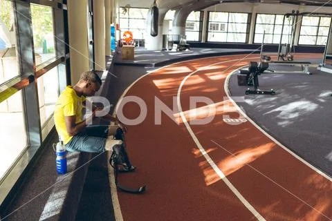 Disabled African American male athletic using mobile phone in fitness center Stock Photos