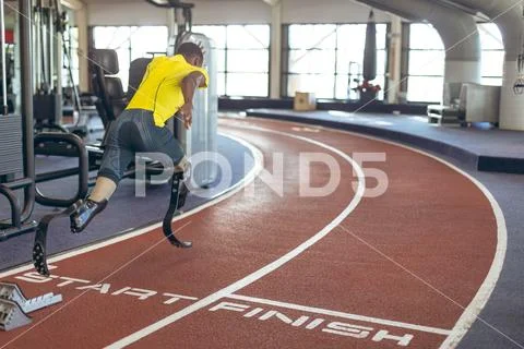 Disabled African American male athletic running on race track in fitness center Stock Photos
