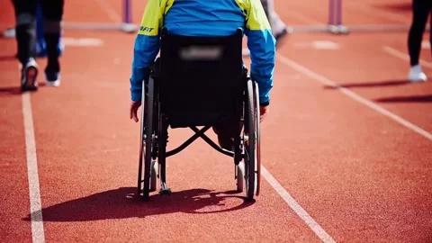 A disabled athlete, a man with leg defects, rides in a wheelchair down the .. Stock Footage 241420312