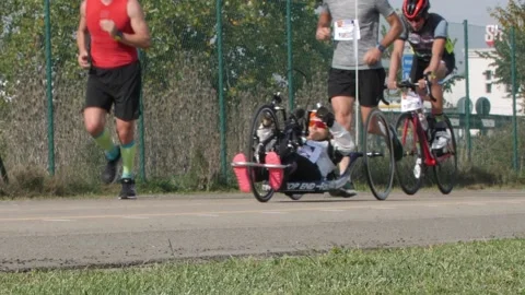 Disabled Athlete training with her Hand bike with Cyclist and Runners Stock Footage 143867977