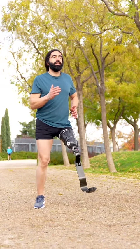 Disabled athletic man running with prosthetic leg in a park Stock Footage 260558216
