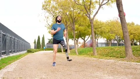 Disabled athletic man running with prosthetic leg in a park Stock Footage 260558711