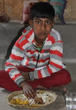 Disabled boy eats from leaf plate in a village in India Stock Photos