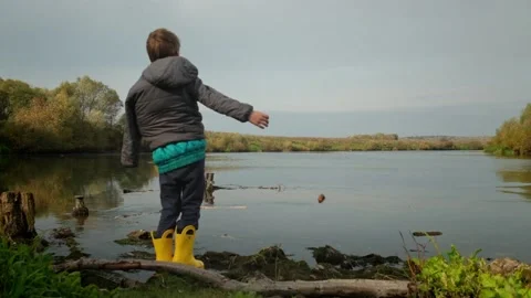 Disabled boy throws a stone into the water. Slow motion Stock Footage 153324627