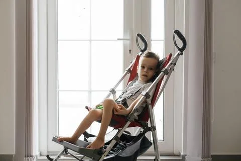 Disabled child in big stroller. Accessibility in wheelchairs and stroller. Stock Photos