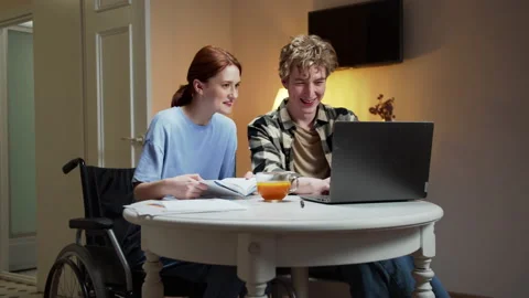 A disabled girl is reading a book while her friend is looking for something on Stock Footage 163478367