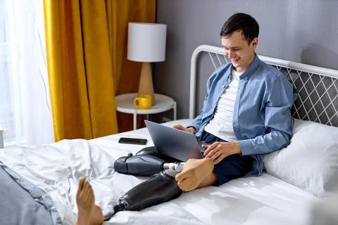 Disabled guy using laptop for work or studies. New normal, social distancing Stock Photos