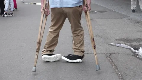 Disabled invalid man with crutches walking down the street Stock Footage 159047257