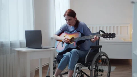 A disabled lady is learning to play the guitar on the Internet Video stock 163477684