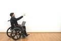 The disabled with a laptop gesturing on the white wall background Photo