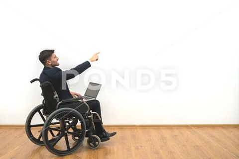 The disabled with a laptop gesturing on the white wall background Stock Photos