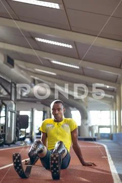 Disabled male athletic relaxing on a running track in fitness center Stock Photos