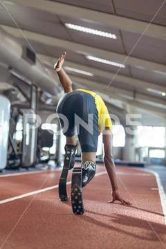 Disabled male athletic running on sports track in fitness center Stock Photos