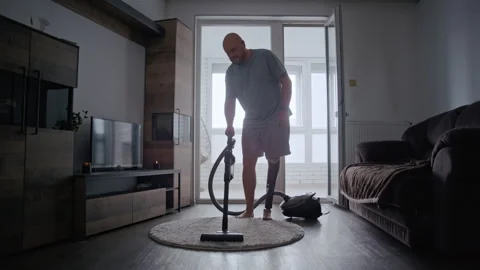 Disabled Man Activates Vacuum Cleaner with Prosthetic Limb at Home Stockbeeldmateriaal 317973729