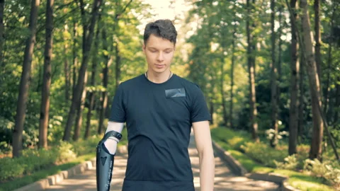 Disabled man with bionic prosthesis stands, crossing his hands. Human with a Stock Footage 94626567