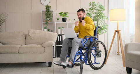 Disabled man dancing and moving around on wheelchair while using laptop Stock Footage 145209069