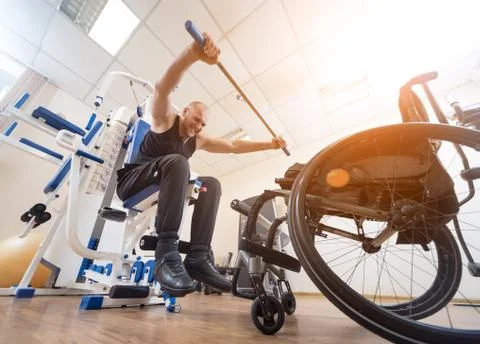 Disabled man doing strength exercises separate from the wheelchair. Stock Photos