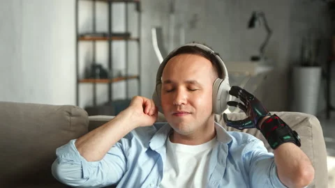 Disabled man with hand prothesis listens to favourite track Stock Footage 157348858