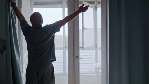 Disabled Man with Prosthetic Leg Opening Curtains to Start New Day 库存影片 317974547