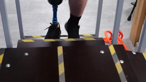 Disabled man with prosthetic leg walking down stairs during physiotherapy Stock Footage 334136950
