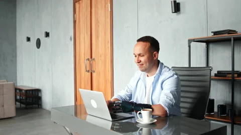 Disabled man with prothesis types on laptop and raises hands Stock Footage 157330224