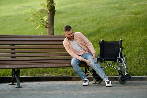 Disabled man transfers from wheelchair to a bench Stock Photos