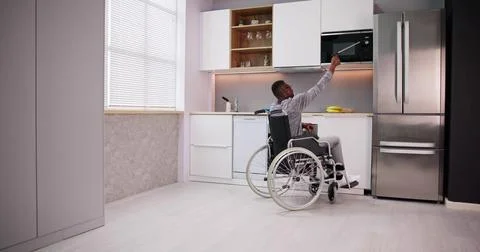 Disabled Man Using Grabber Tool To Control Microwave Stock Photos