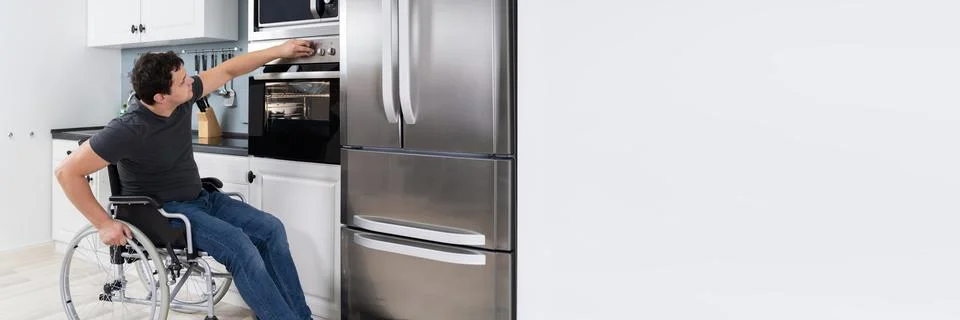 Disabled Man Using Microwave Oven In Kitchen Stock Photos