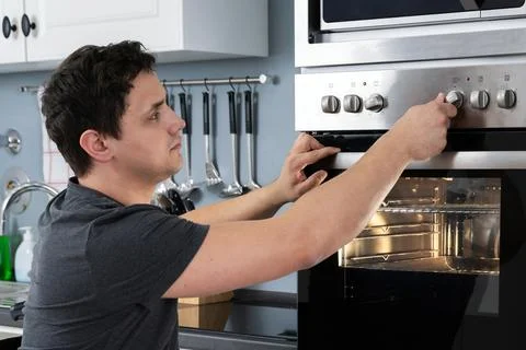 Disabled Man Using Microwave Oven In Kitchen Stock Photos