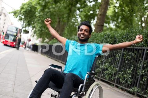 Disabled man in a wheelchair celebrating Stock Photos