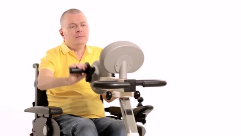 A disabled man in a wheelchair doing exercises for his hands and foots Stock Footage 233371962