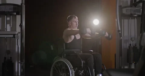Disabled man in a wheelchair performs exercises with dumbbells. Stock Footage 147044638