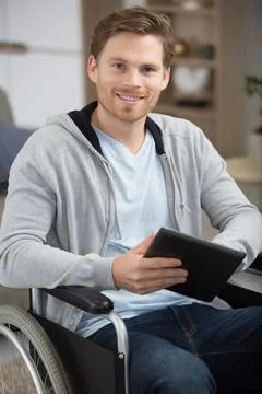 Disabled man in a wheelchair using a tablet computer Stock Photos