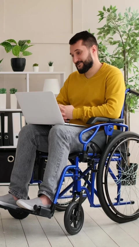 Disabled Man in Wheelchair Video Calling on Laptop at Home Stock Footage 328122744