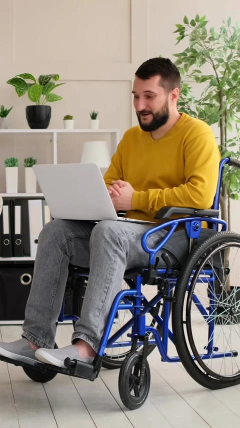 Disabled Man in Wheelchair Video Calling on Laptop at Home Stock Footage 328122746
