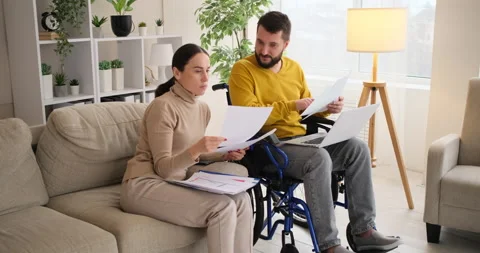 Disabled man with wife doing paperwork while working on laptop Stock Footage 145253302