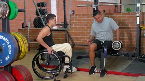 Disabled men with prosthetic leg and wheelchair training at gym Stock Footage 317759696