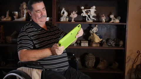 DISABLED-PARAPLEGIC: man with tablet computer in wheelchair playing video game Stock Footage 45437454