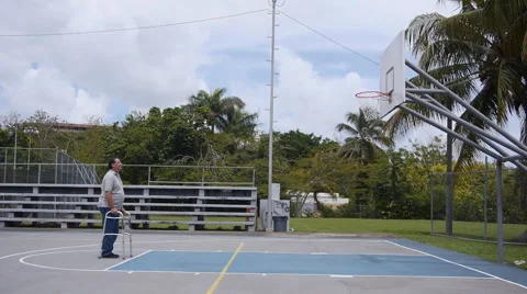 DISABLED-PARAPLEGIC: Old man with walking frame looks at basketball ring Stock Footage 51054789