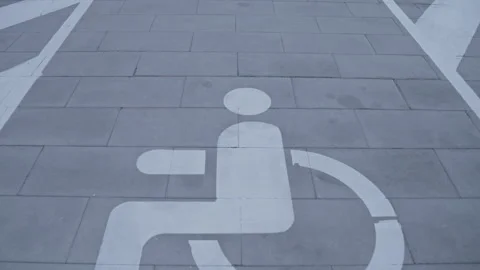Disabled parking sign gradually emerging on gray urban pavement Stock Footage 295953245