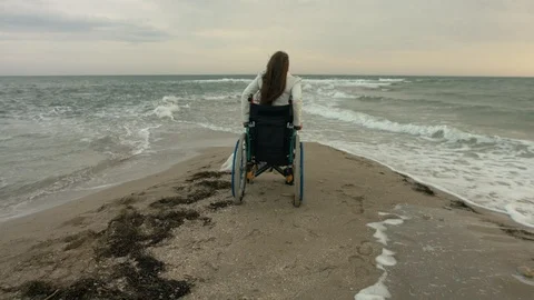 The disabled person gets out of the stroller on the shore of the sea Stock Footage 95218760
