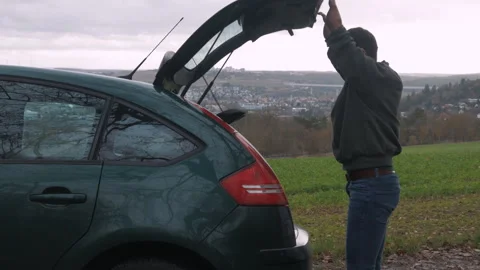 The disabled person opens the trunk of the car and takes out things. Stock Footage 268975809