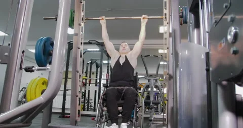 Disabled person in a wheelchair pulls up on a horizontal bar in the gym. Stockbeeldmateriaal 147044167