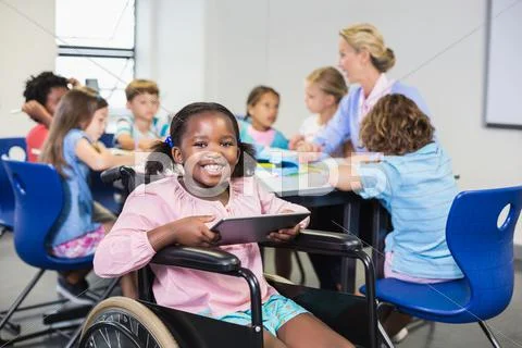 Disabled Schoolgirl Using Digital Tablet In Classroom At School