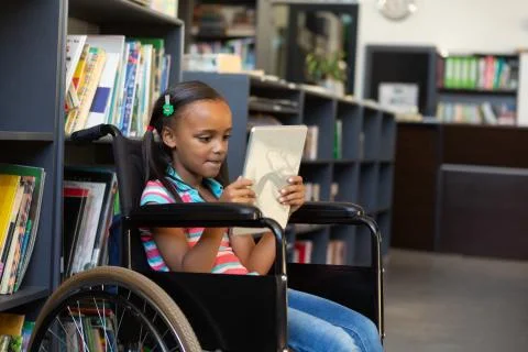 Disabled schoolgirl using digital tablet in the library Foto stock